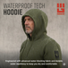 Man wearing olive drab green waterproof tech hoodie in heavy rain, hood up